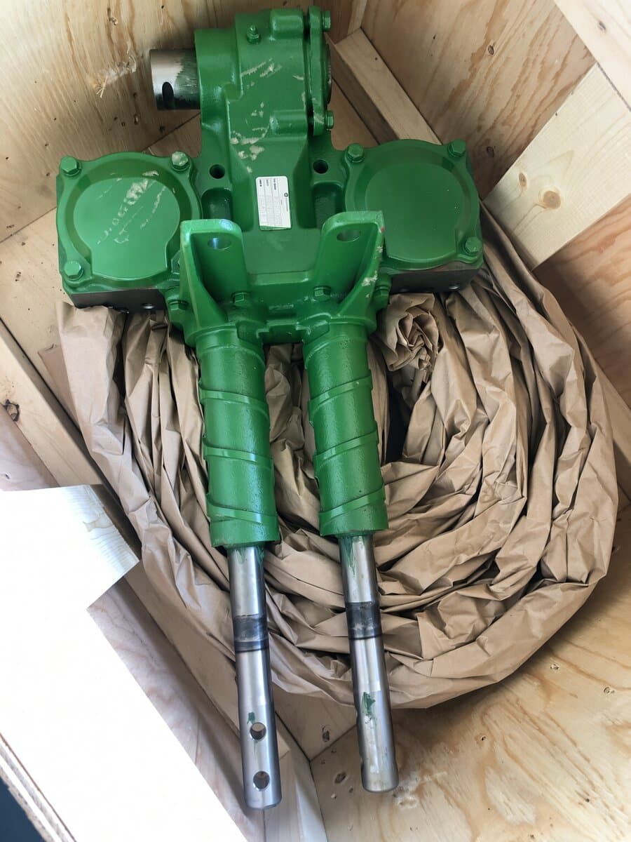 Green hydraulic cylinder assembly cushioned in kraft paper inside a wooden crate