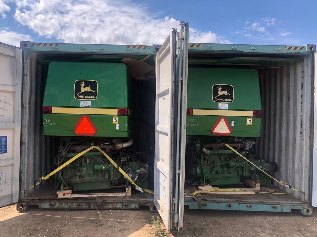 Two John Deere engine modules strapped inside two side by side shipping containers